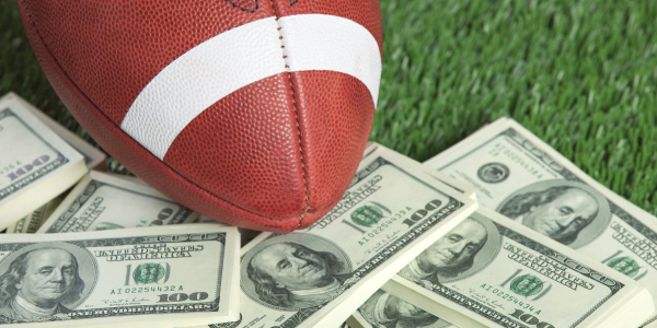 Football sitting on a pile of $100 bills