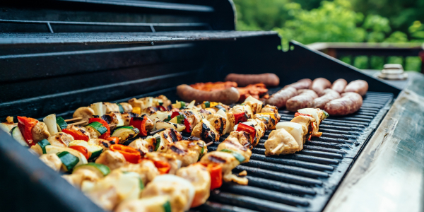 Barbeque grill showing sausages and vegetable skewers